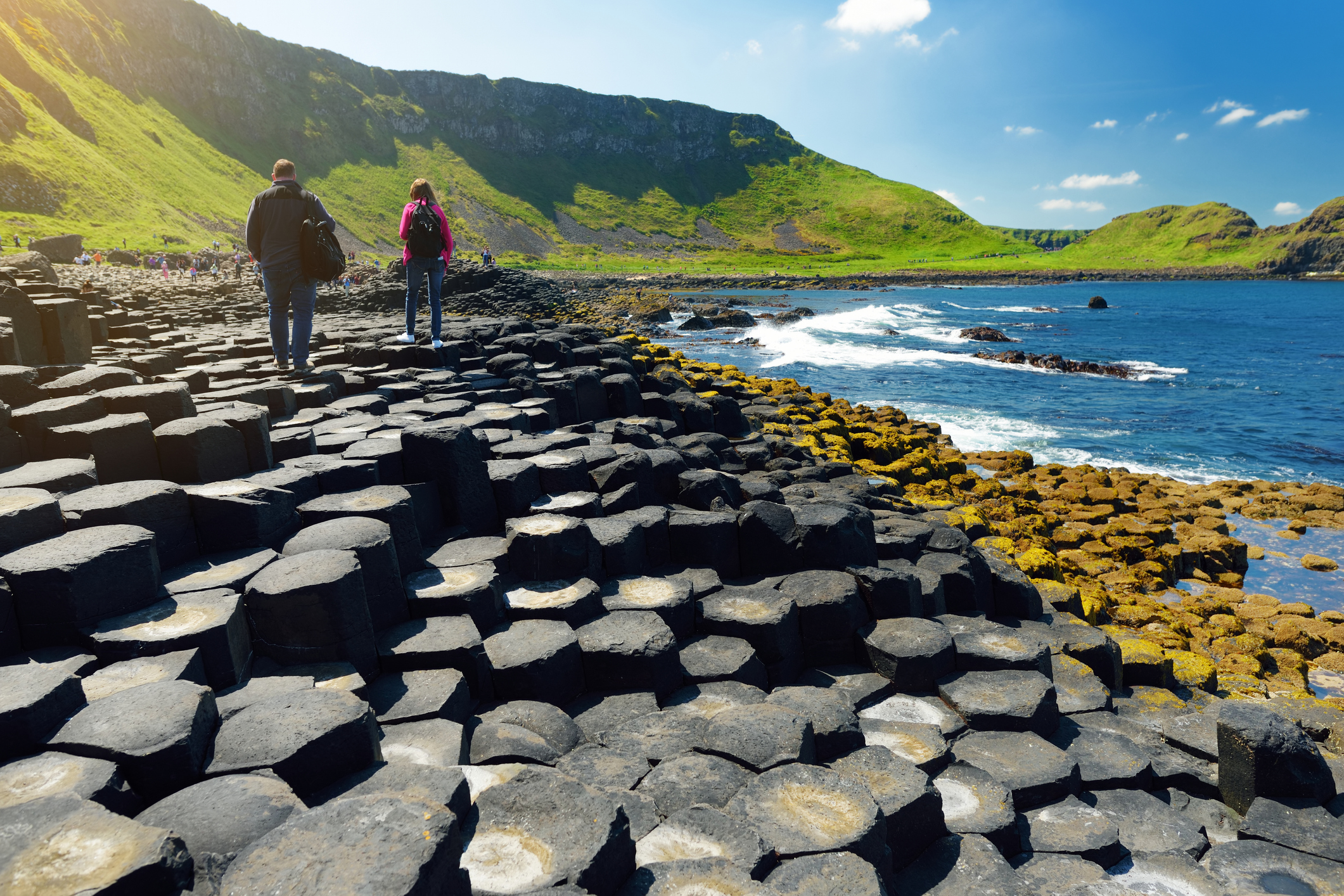 Two tourists walking at Giants Causeway, an area of hexagonal basalt stones, County Antrim, Northern Ireland. Famous tourist attraction, UNESCO World Heritage Site.