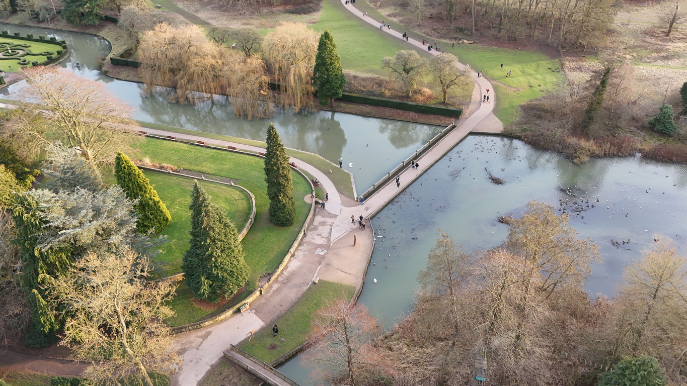 Aerial view of a scenic park with pathways, trees, a pond, and people strolling. Coventry, UK